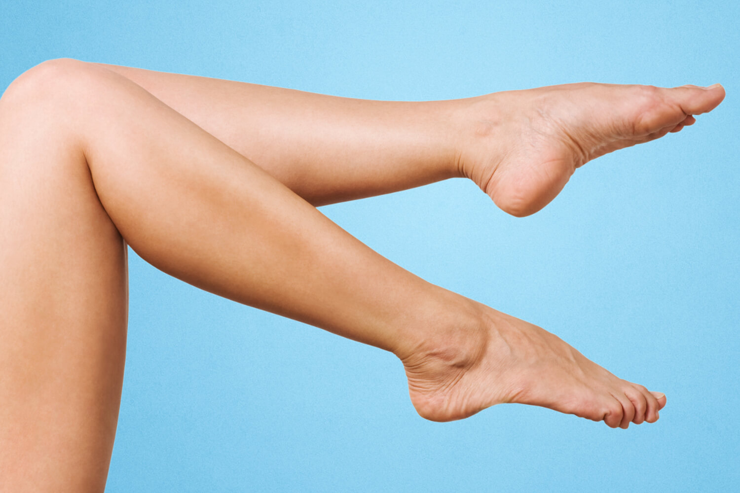 A pair of female legs in the air against a plain background