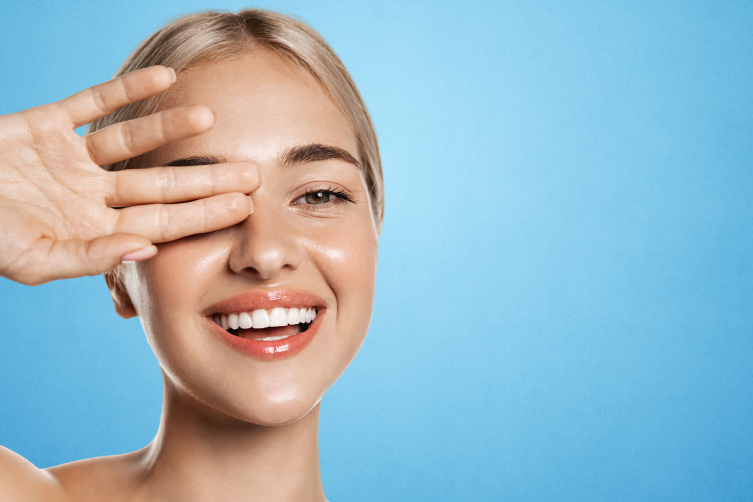 Woman holds hand over one eye.