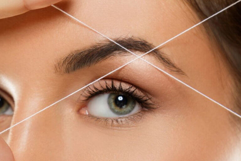 Example photo of a brow threading - two threads intersect below a woman's eyebrow