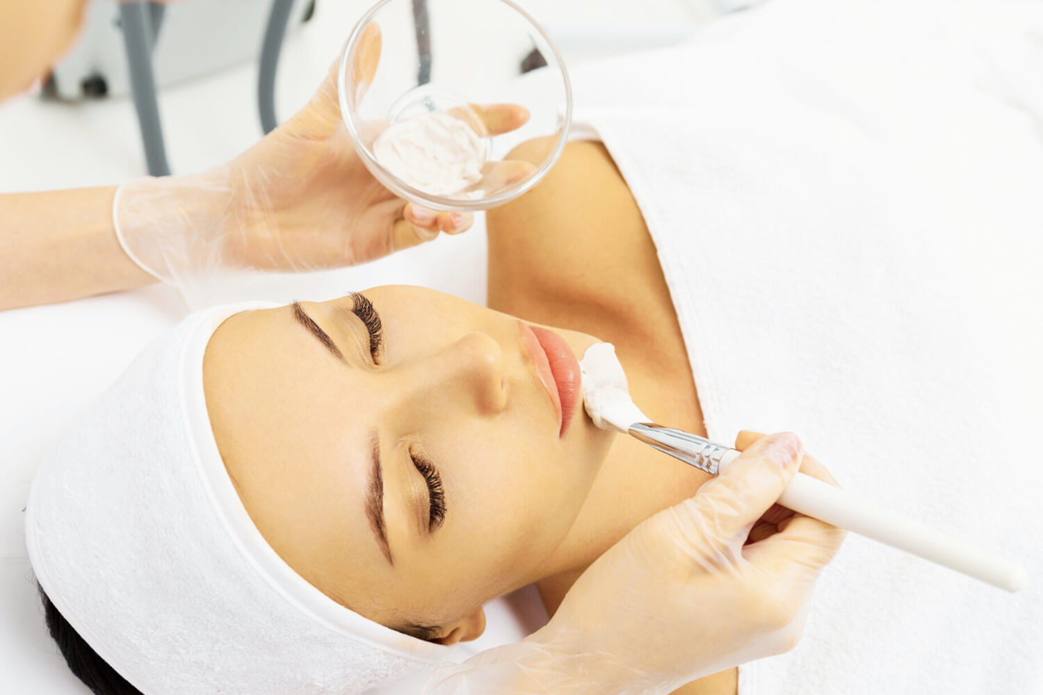 Woman at spa having skin care treatment painted on face