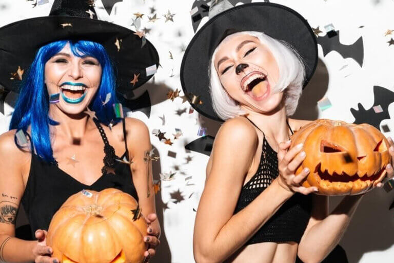 Two women dressed up for Halloween holding Jack-o'-lanterns